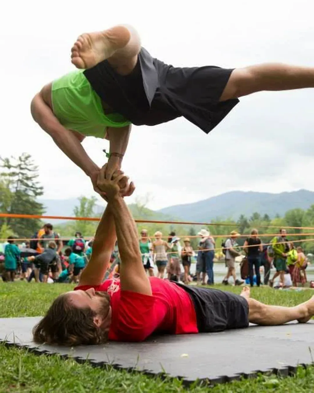 Rob Lenfestey in an acro-yoga arm balance, holding a partner overhead in the Blue Ridge Mountains